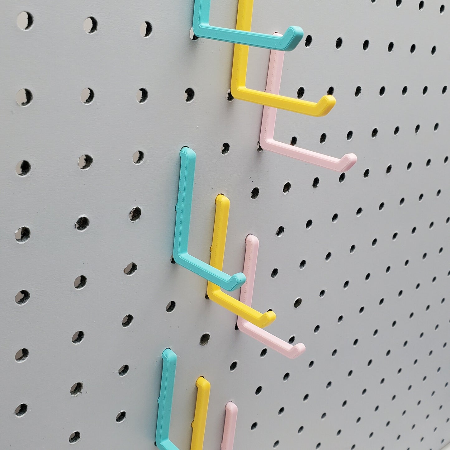 Light Pink, Teal and Savannah Yellow L-Hooks on a 1/4" Pegboard. Three sizes, Small, medium, large.