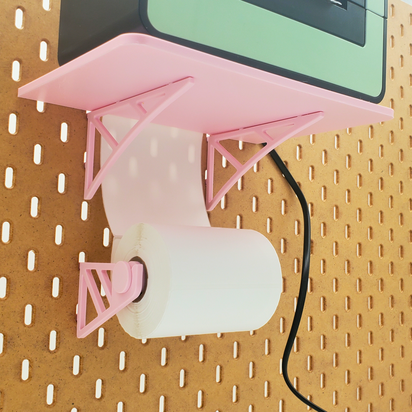 Roll of shipping labels mounted to Light Pink Thermal Printer shelf for IKEA SKADIS pegboards.