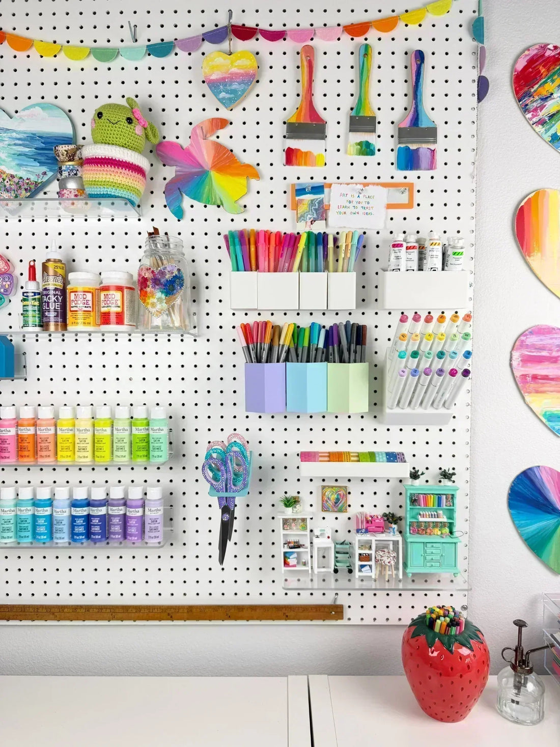 Colorful craft room pegboard organized with marker holders, paint storage, shelves, and creative supplies in the Color Made Happy studio.