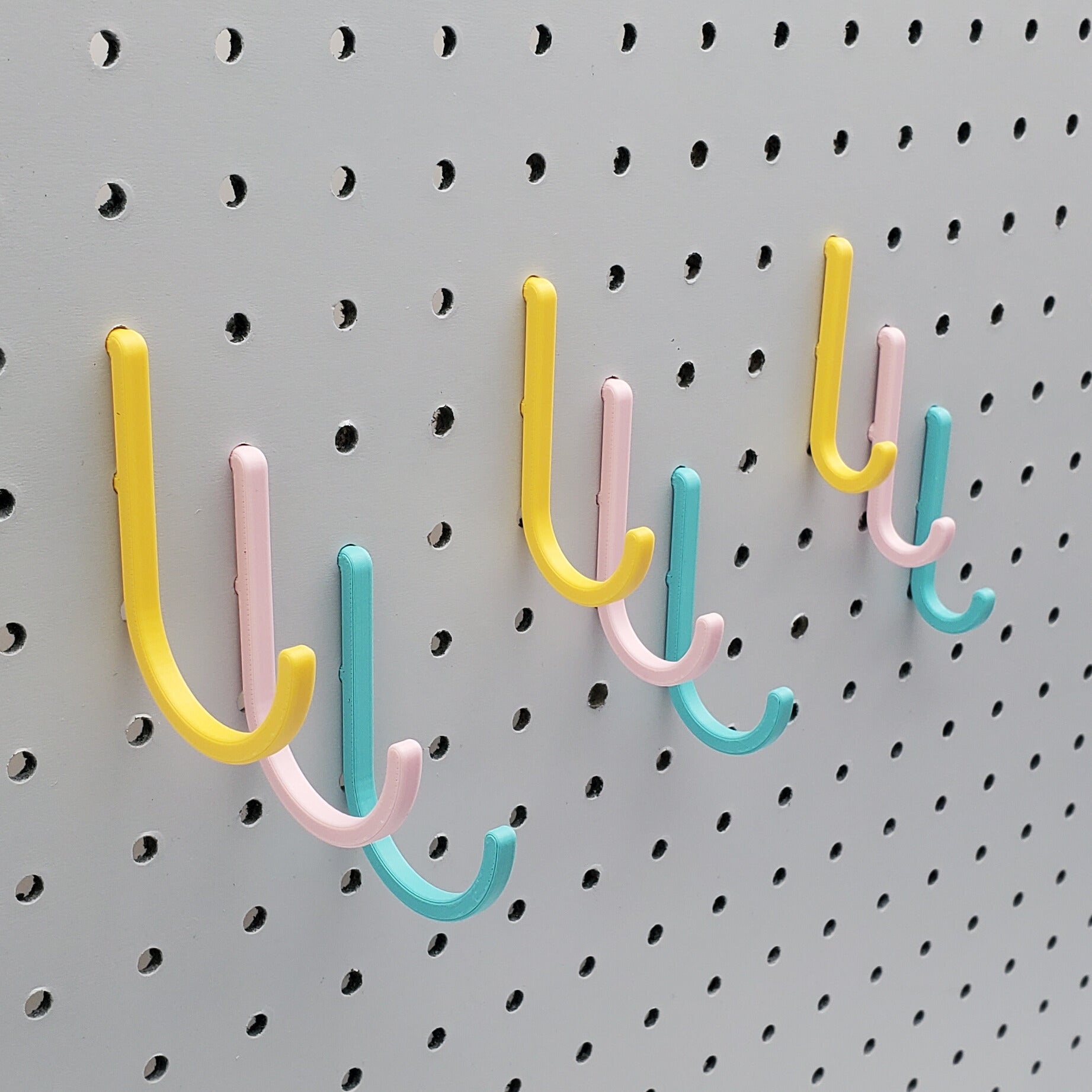 Light Pink, Teal, and Savannah Yellow J-Hooks for 1/4" Pegboards. Displaying all three sizes.