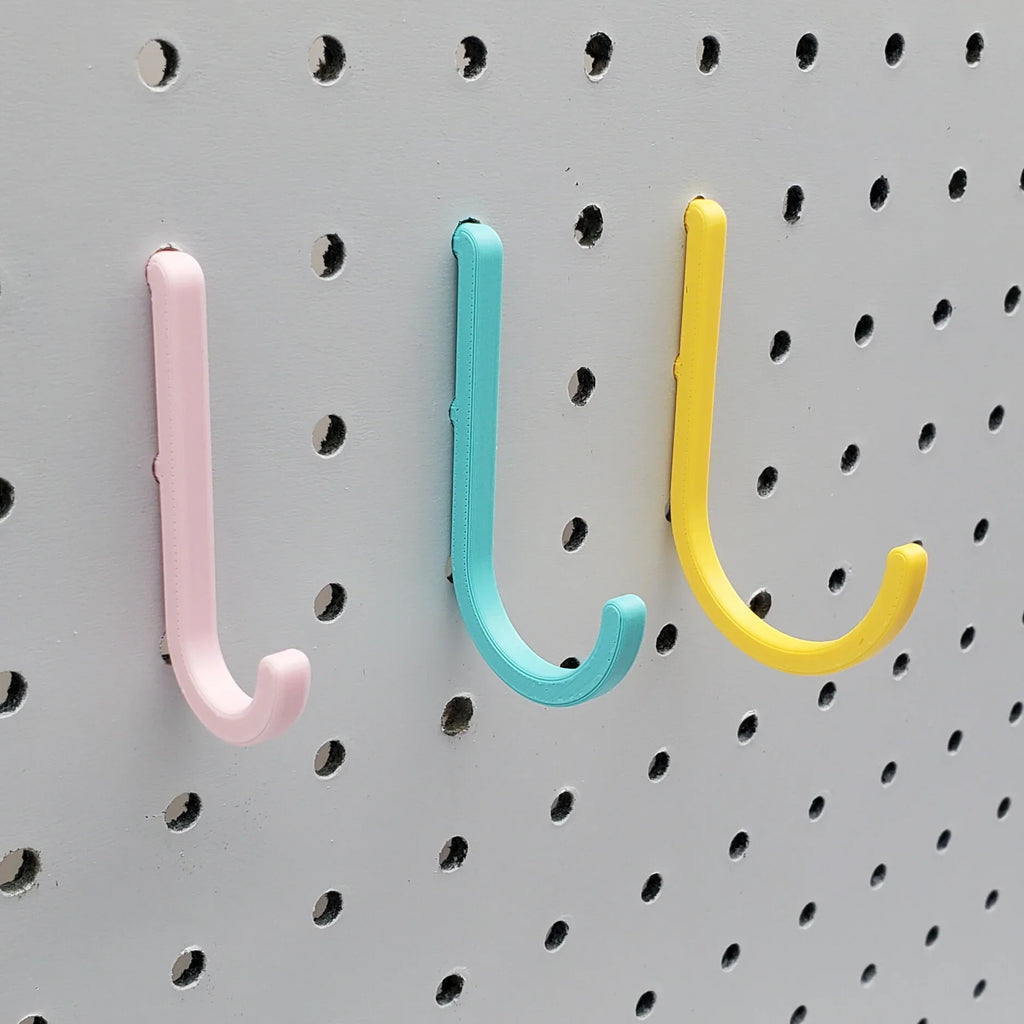 Small, Medium, and Large J Hooks in Light Pink, Teal, and Savannah Yellow on 1/4" pegboard.
