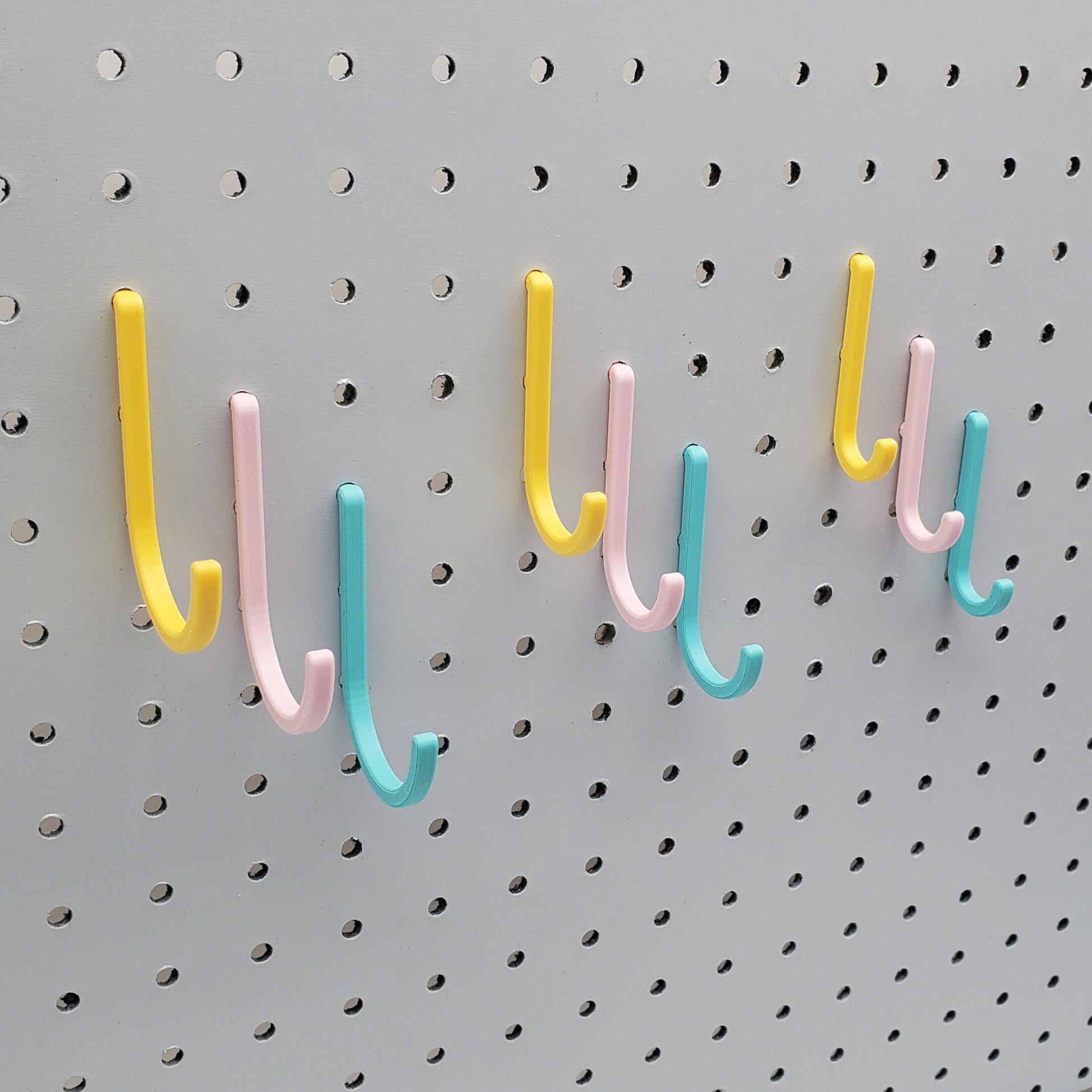 Light Pink, Teal, and Savannah Yellow J-Hooks for 1/4" Pegboards. Displaying all three sizes.