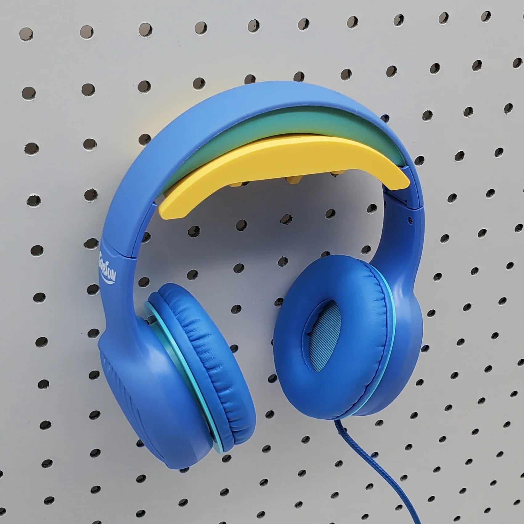 Headphone Holder in Savannah Yellow with blue headphones on 1/4" pegboard.