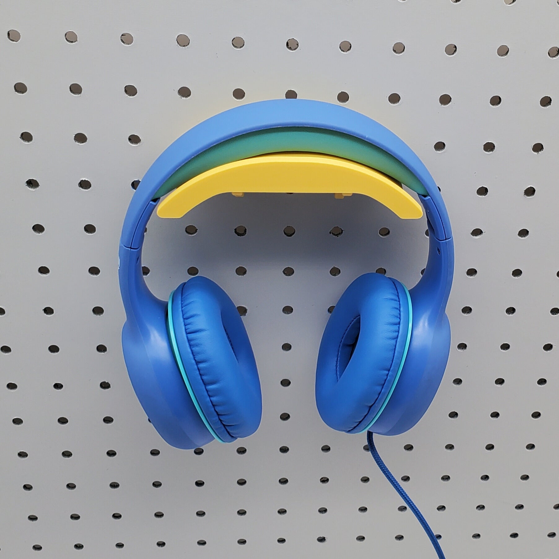 Yellow headphone holder with a blue headphone displayed on a pegboard.