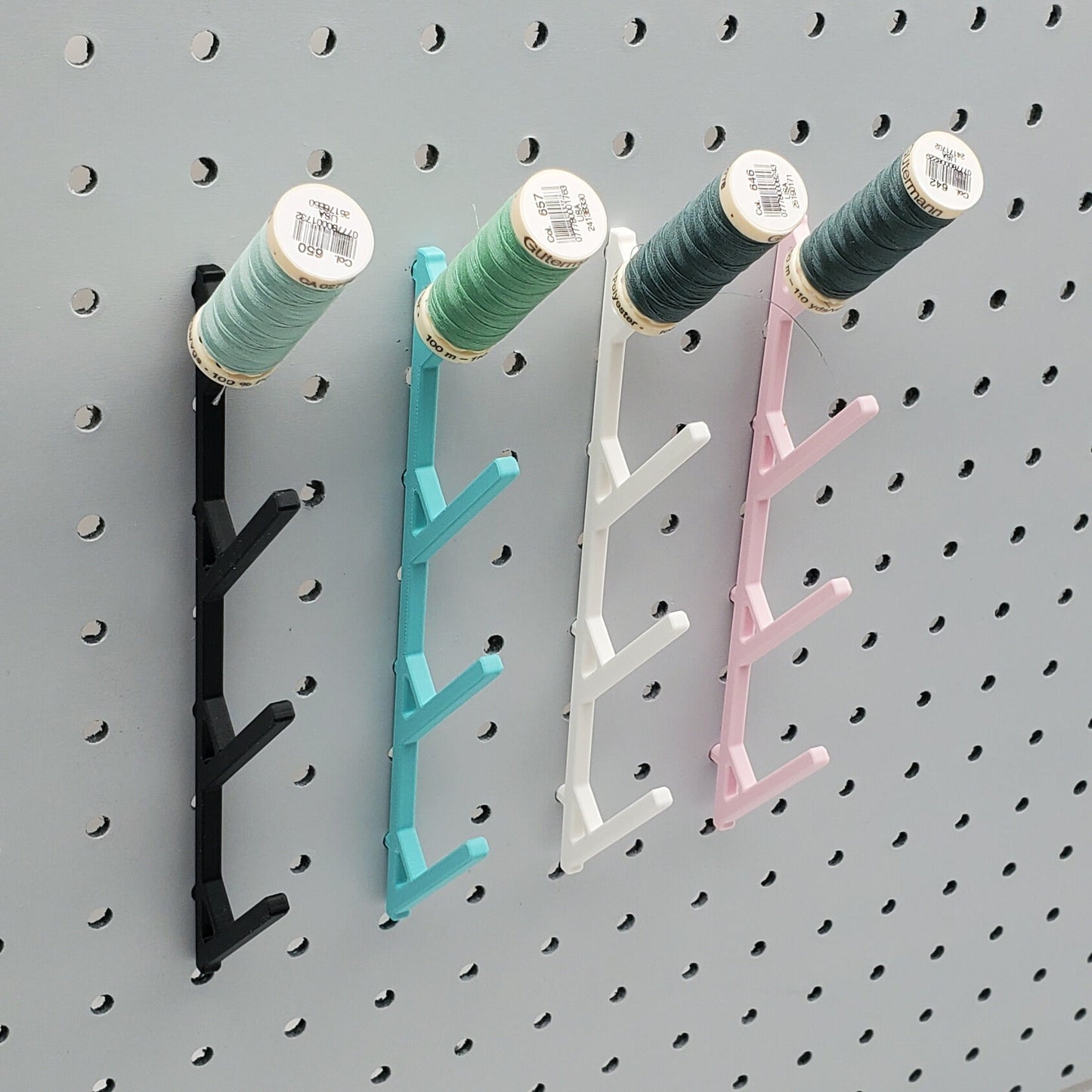 Four Medium Thread Racks in Charcoal Black, Teal, Cotton White, and Light Pink on 1/4" pegboard with spools.