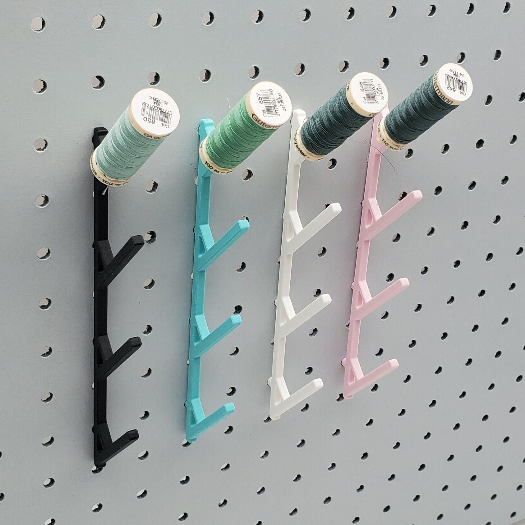 Four Medium Thread Racks in Charcoal Black, Teal, Cotton White, and Light Pink on 1/4" pegboard with spools.