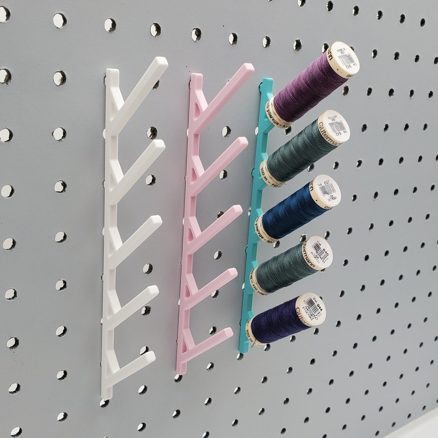 Three Small Thread Racks in Cotton White, Light Pink, and Teal on 1/4" pegboard with thread.