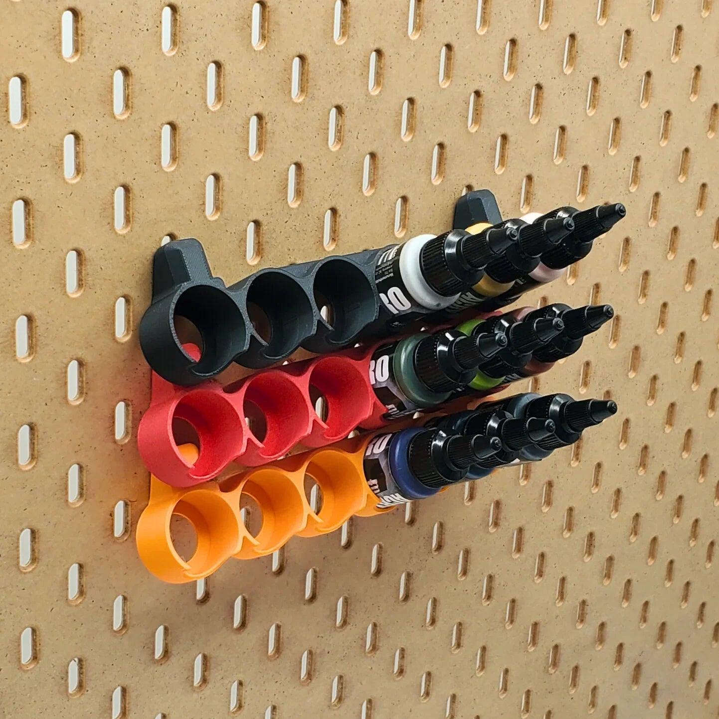 Three 22mL Pro Acryl paint racks in Sunrise Orange, Lava Red, and chacoal black on IKEA SKADIS pegboard.