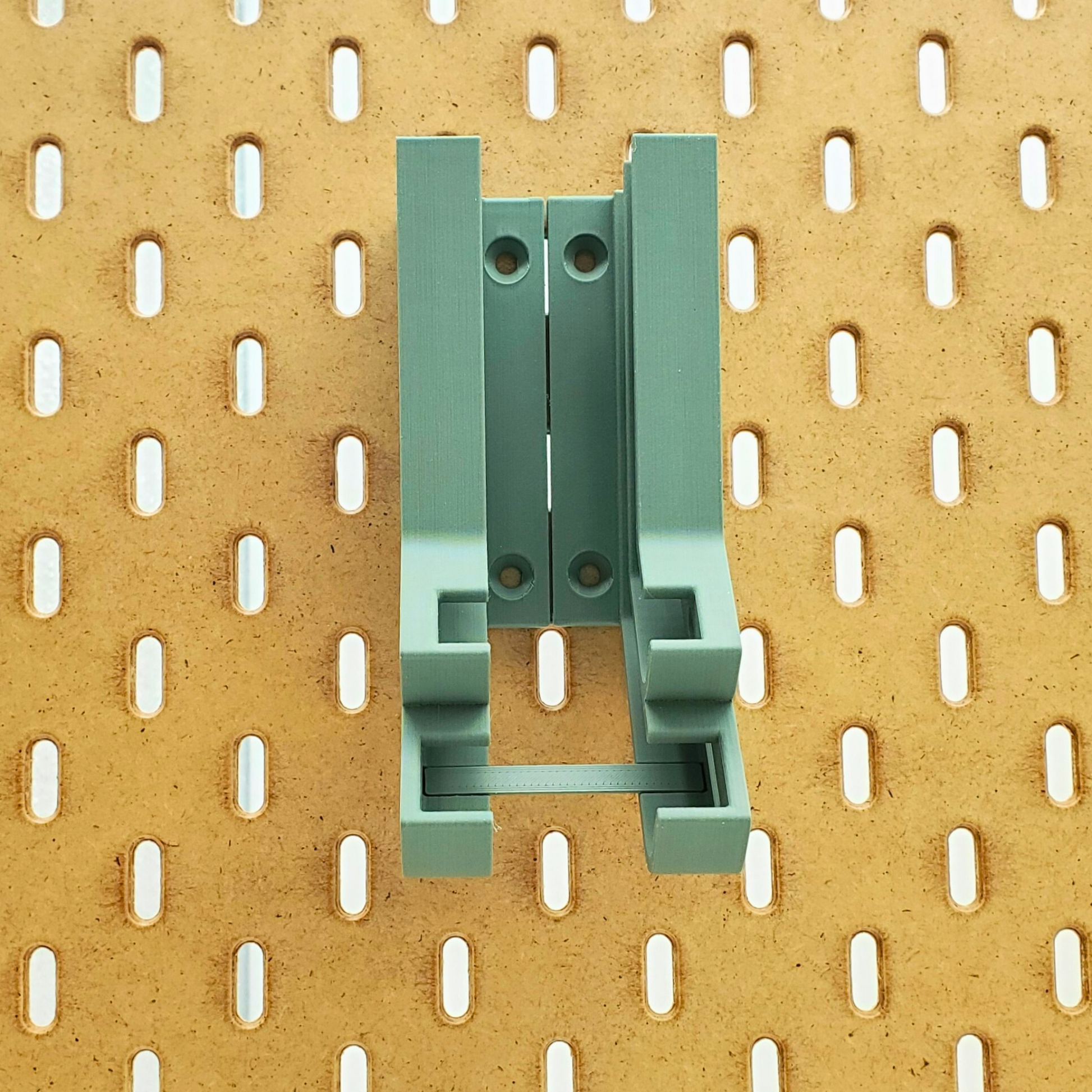 Front view of muted green battery dispenser with backing bar installed