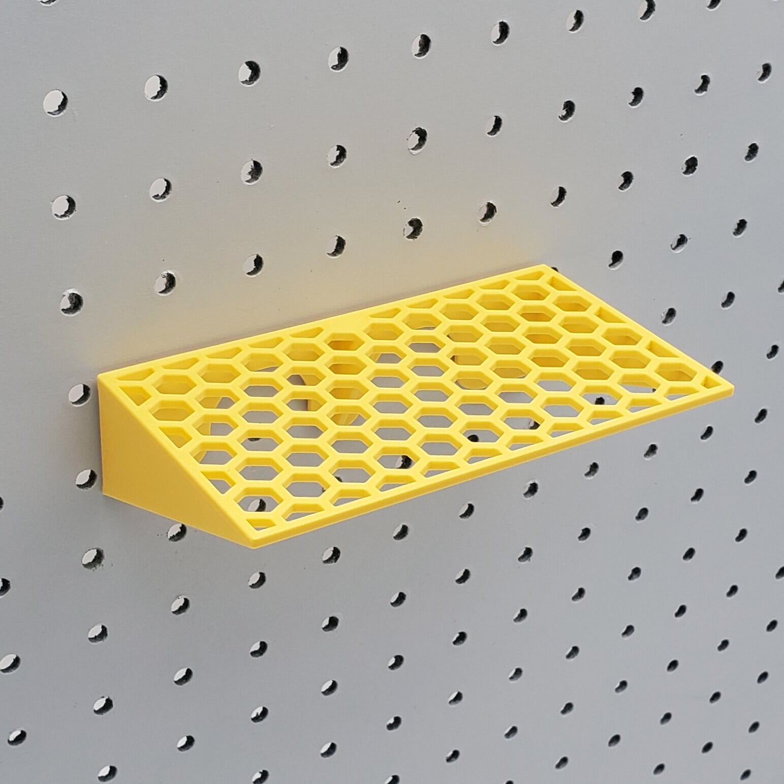 Top view of yellow screwdriver holder on a pegboard with no props.