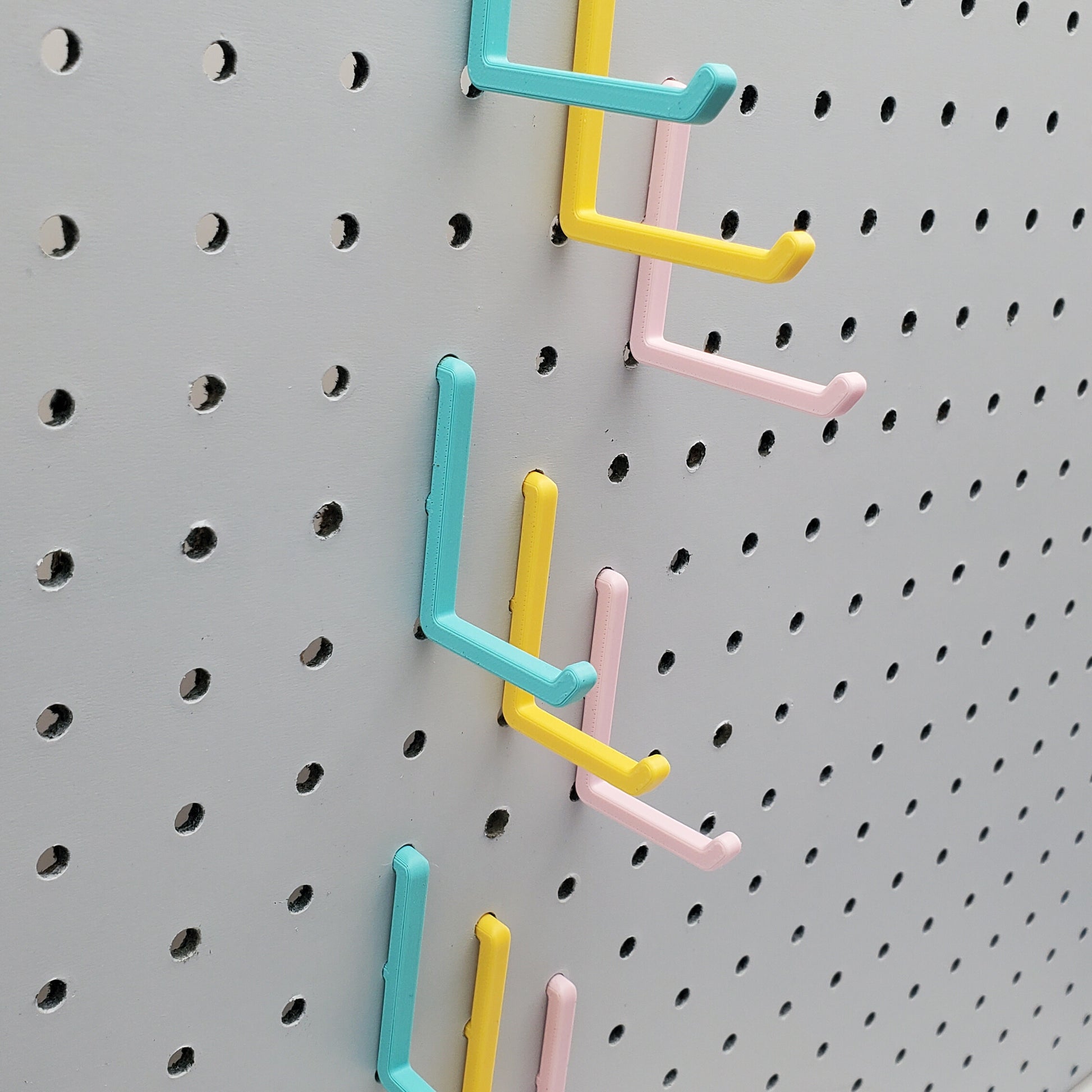 Light Pink, Teal and Savannah Yellow L-Hooks on a 1/4" Pegboard. Three sizes, Small, medium, large.