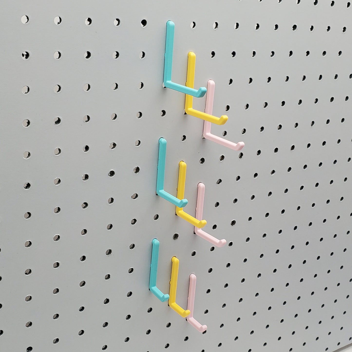 Light Pink, Teal and Savannah Yellow L-Hooks on a 1/4" Pegboard. Three sizes, Small, medium, large of all three colors.
