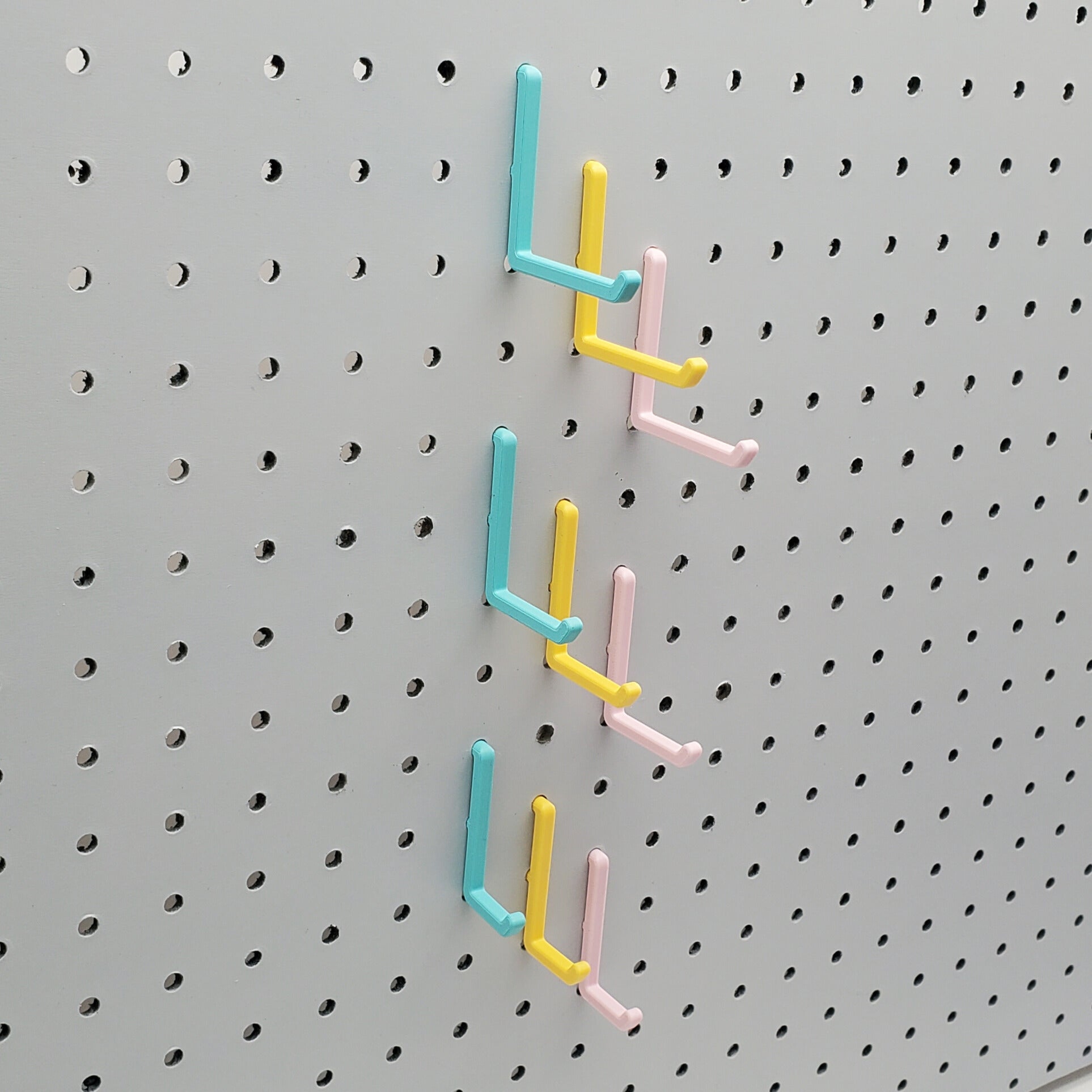 Light Pink, Teal and Savannah Yellow L-Hooks on a 1/4" Pegboard. Three sizes, Small, medium, large of all three colors.