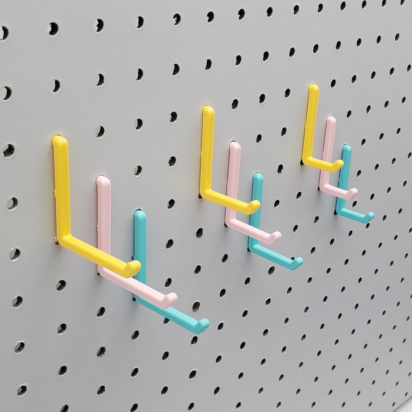 Light Pink, Teal and Savannah Yellow L-Hooks on a 1/4" Pegboard. Three sizes, Small, medium, large. All three colors