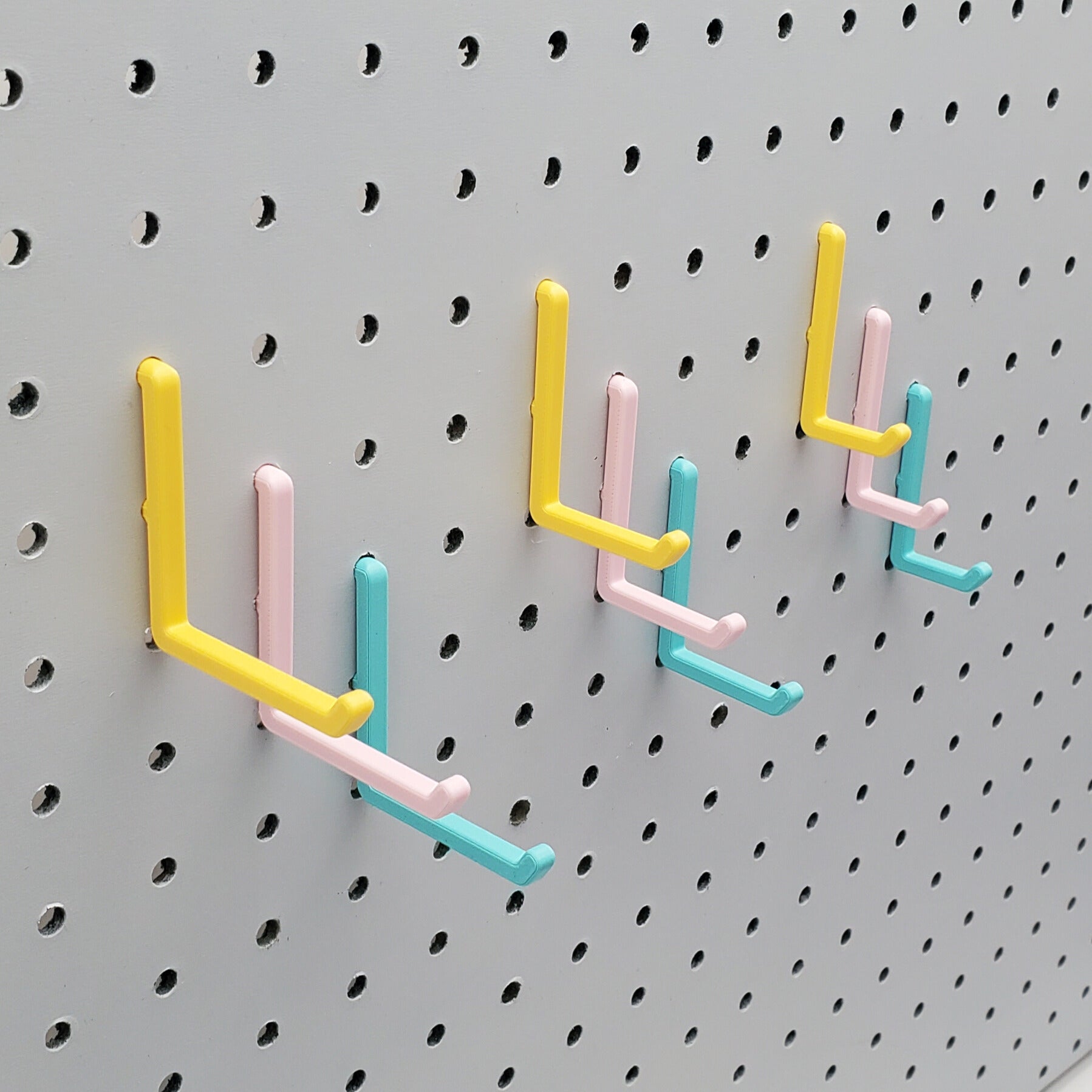 Light Pink, Teal and Savannah Yellow L-Hooks on a 1/4" Pegboard. Three sizes, Small, medium, large. All three colors