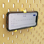 iPhone and Tablet Holder in Savannah Yellow on IKEA SKADIS pegboard with iPhone.