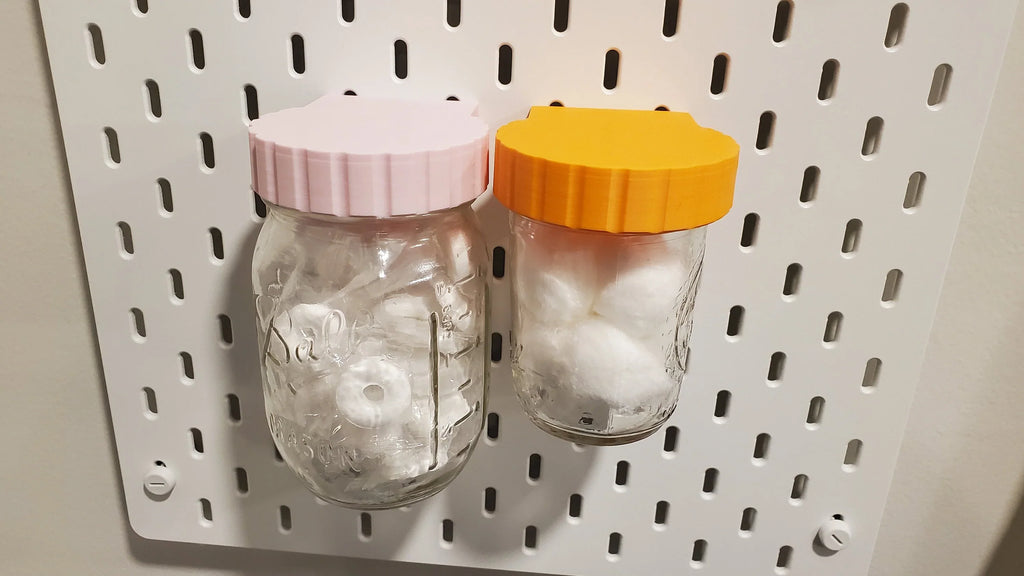 Mason Jar Storage lids in Light Pink and Sunrise Orange on IKEA SKADIS pegboard.