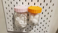 Mason Jar Storage lids in Light Pink and Sunrise Orange on IKEA SKADIS pegboard.