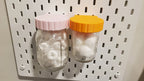 Mason Jar Storage lids in Light Pink and Sunrise Orange on IKEA SKADIS pegboard.